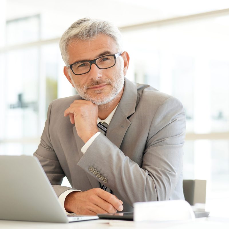 Mature businessman sitting at desk looking at camera